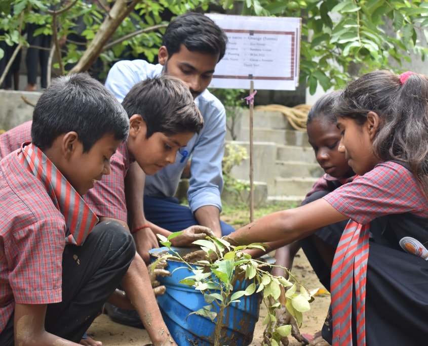 Indische Kinder pflanzen Bäume während Workshop im Schulhaus