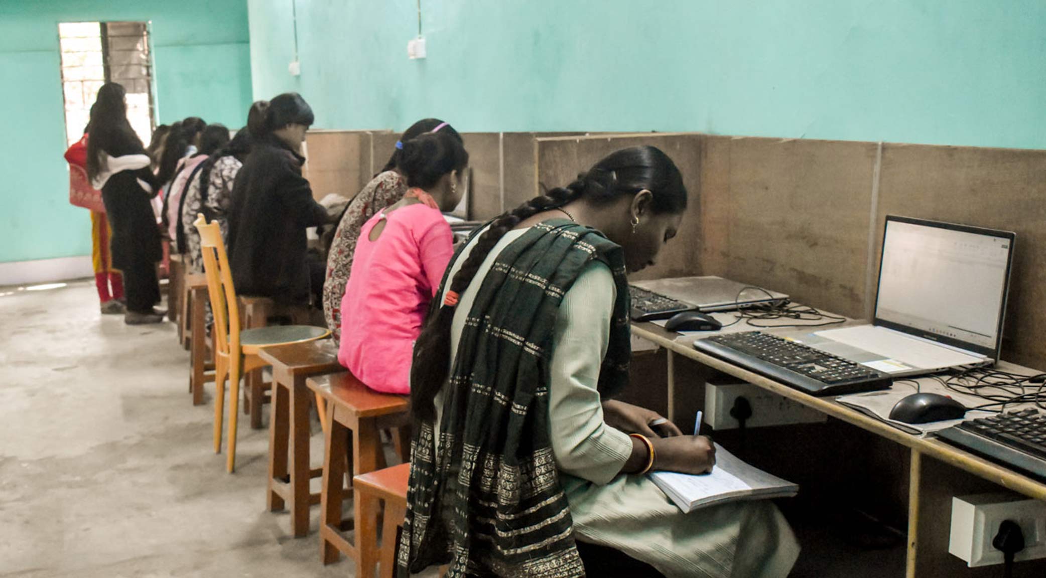 Titelslider Mehrere Frauen sitzen in einem Computerkurs vor Bildschirmen. Man sieht sie von hinten.