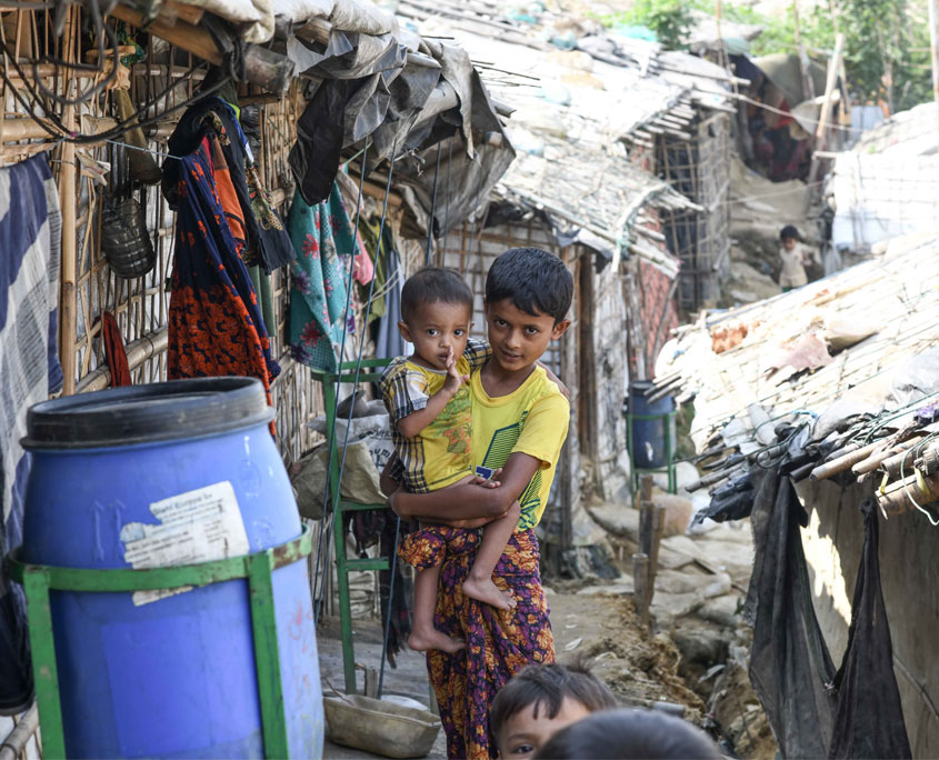 Rohingya-Camp-Blick-ins-innere In einer informellen Siedlung im Flüchtlingslager bei Cox's Bazar trägt ein Junge ein Kleinkind am Arm.