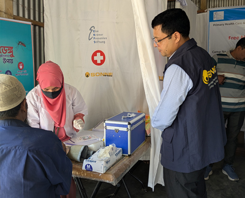 Blick in eine Sonne gesundheitsstation in Bangladesch. im vordergrund ein Mann und eine gesundheitsarbeiterin.