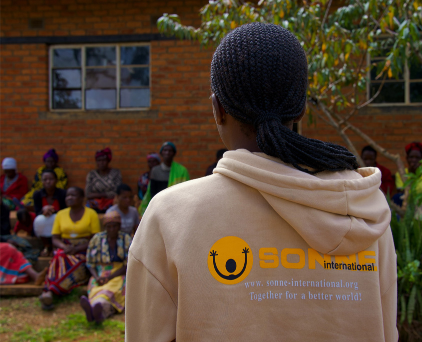 Malawi-Nothilfe-7 Eine SONNE-Mitarbeiterin von hinten, die sich den Frauen zuwendet, die auf die Hilfslieferungen wartet