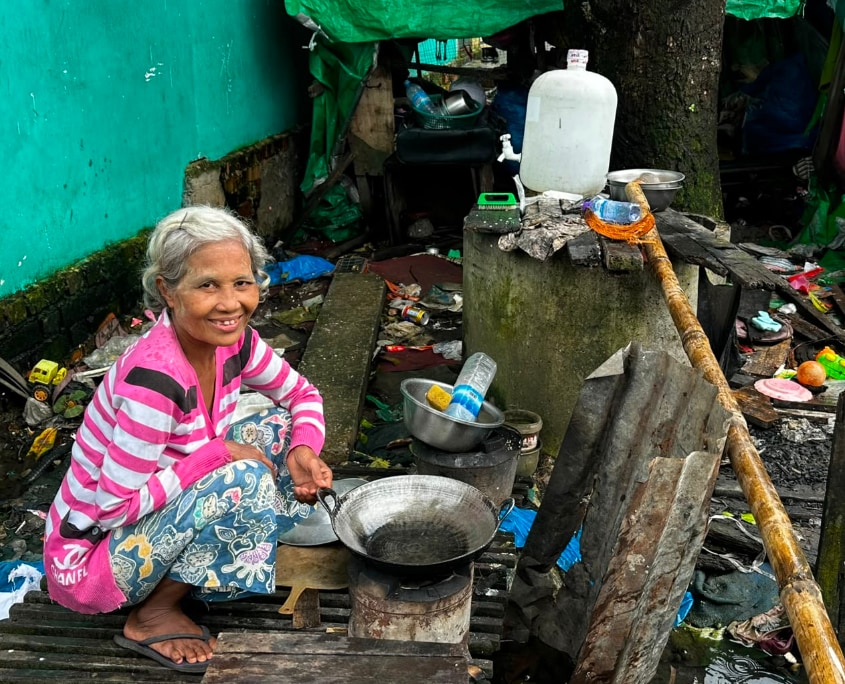 DCC4_im Slum 01 Beitrags_854_c_SONNE-International2026 Frau in den Slums von Yangon, kocht vor ihrer Hütte